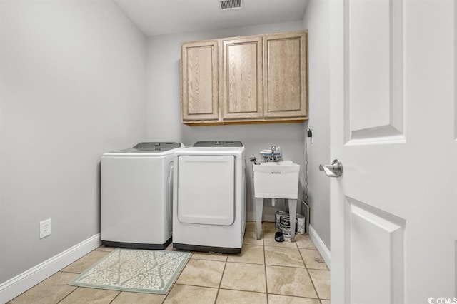 laundry room featuring cabinets, separate washer and dryer, and light tile patterned floors