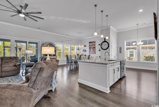 kitchen featuring sink, decorative light fixtures, a center island with sink, light stone countertops, and white cabinets