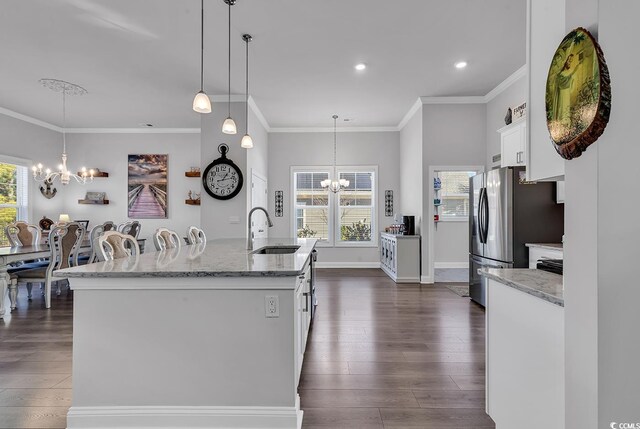 kitchen featuring pendant lighting, sink, white cabinetry, a center island with sink, and a chandelier