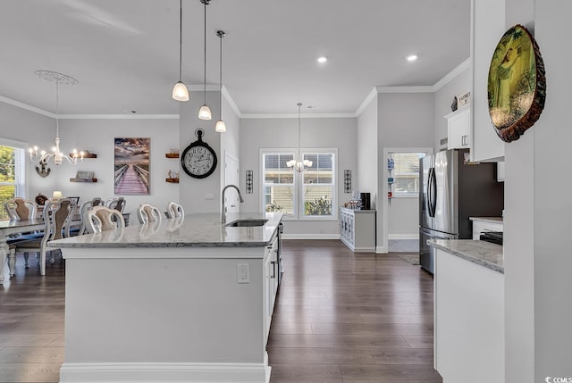 kitchen with dark wood finished floors, an inviting chandelier, white cabinetry, a sink, and baseboards