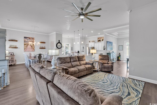 living room featuring crown molding, ceiling fan with notable chandelier, and hardwood / wood-style flooring