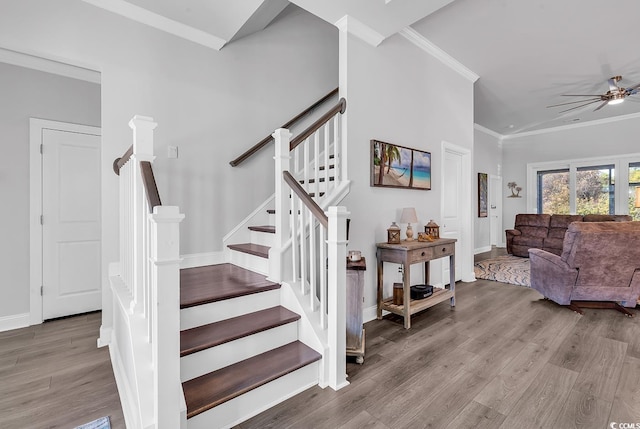 stairway with ornamental molding, wood finished floors, a ceiling fan, and baseboards