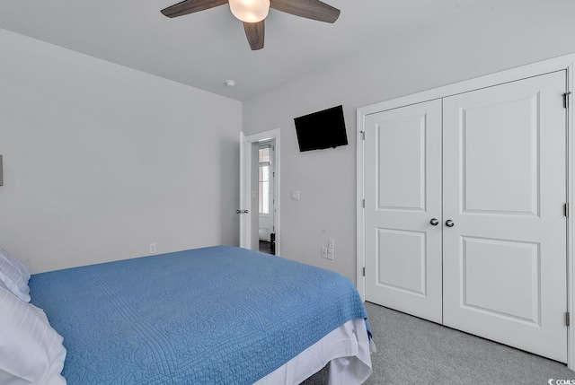 bedroom with light colored carpet, ceiling fan, and a closet