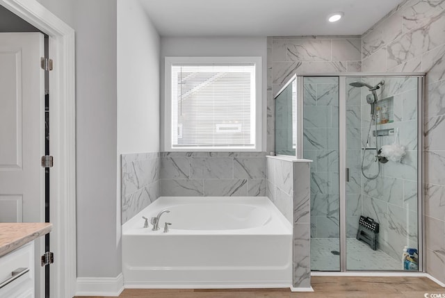 bathroom with a stall shower, a garden tub, and vanity