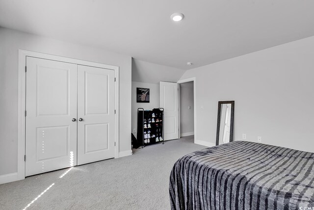 bedroom featuring baseboards, vaulted ceiling, a closet, and light colored carpet