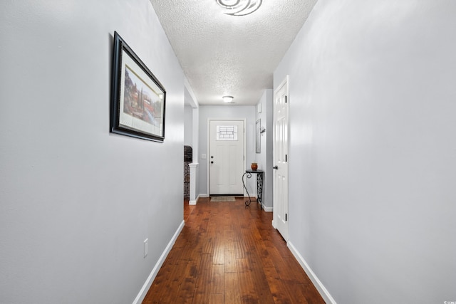 corridor with wood-type flooring and a textured ceiling