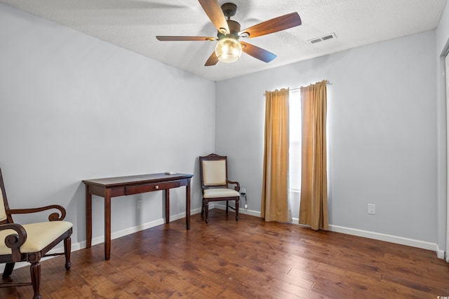 living area with ceiling fan, dark hardwood / wood-style floors, and a textured ceiling