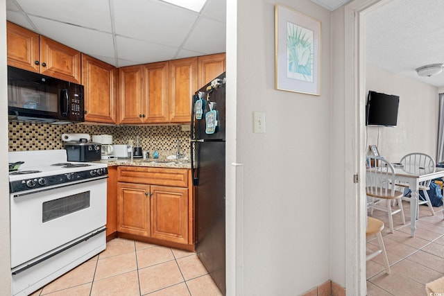 kitchen with sink, black appliances, light tile patterned floors, decorative backsplash, and a drop ceiling