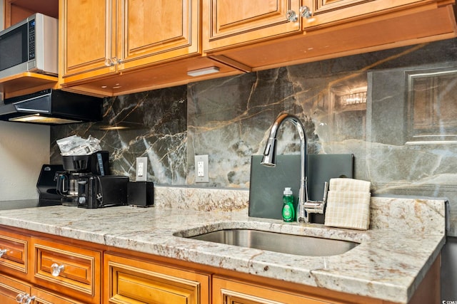 kitchen with light stone countertops, sink, and decorative backsplash