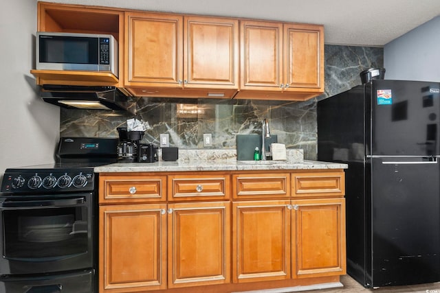 kitchen featuring backsplash, light stone counters, and black appliances