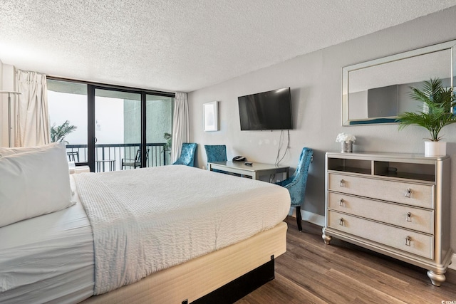 bedroom featuring dark hardwood / wood-style flooring, a textured ceiling, access to exterior, and a wall of windows