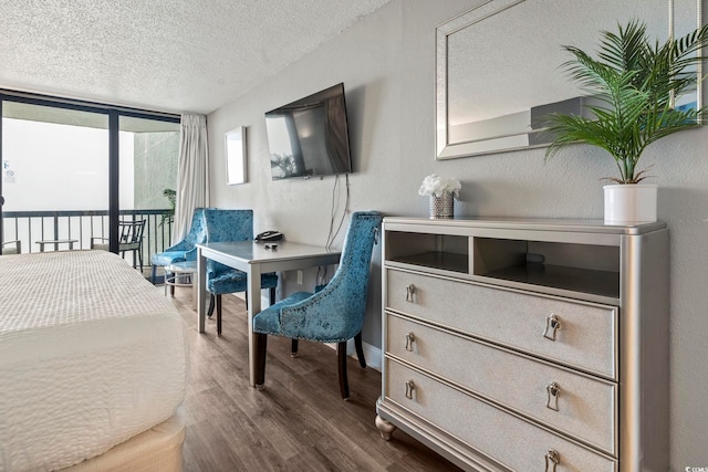 bedroom featuring a wall of windows, access to exterior, hardwood / wood-style floors, and a textured ceiling