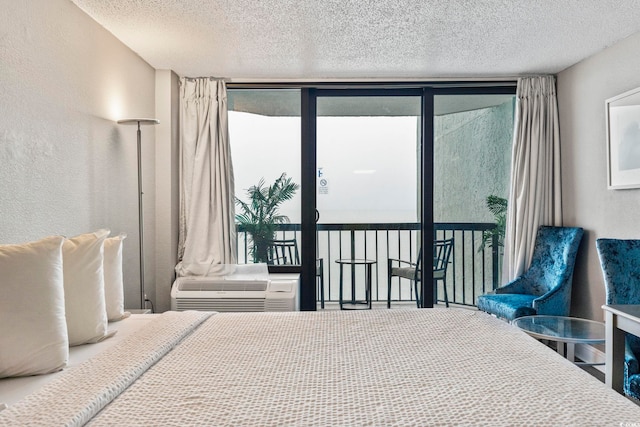 bedroom featuring access to outside, floor to ceiling windows, and a textured ceiling