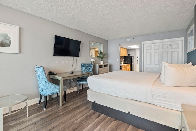 bedroom featuring black refrigerator, hardwood / wood-style floors, a closet, and a textured ceiling