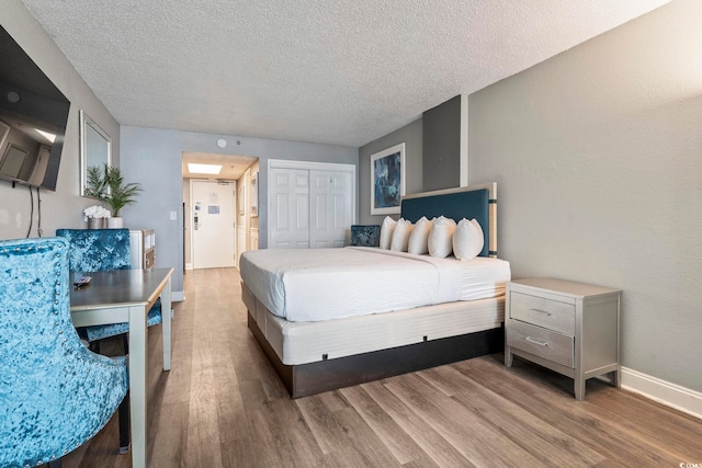 bedroom with a closet, wood-type flooring, and a textured ceiling