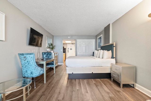 bedroom with wood-type flooring, a textured ceiling, and a closet