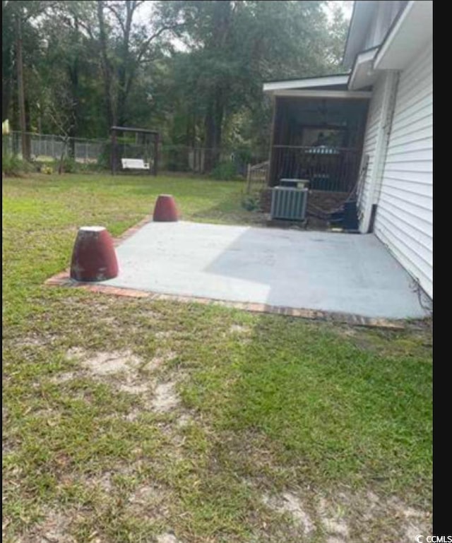 view of storm shelter with central AC unit, a yard, and a patio area