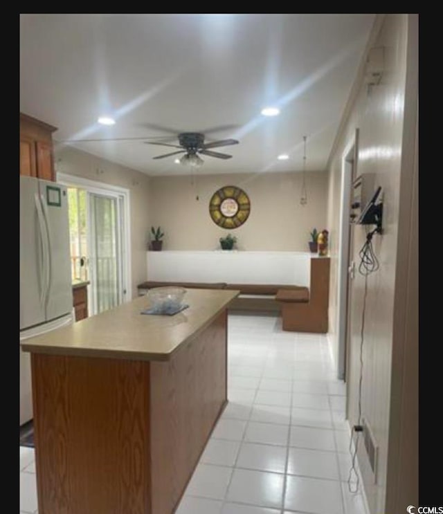 kitchen featuring white refrigerator, ceiling fan, light tile patterned flooring, and a kitchen island