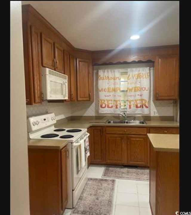 kitchen featuring sink, white appliances, light tile patterned floors, and decorative backsplash