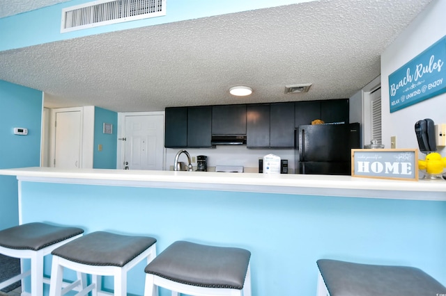 kitchen with a kitchen bar, sink, kitchen peninsula, and black fridge