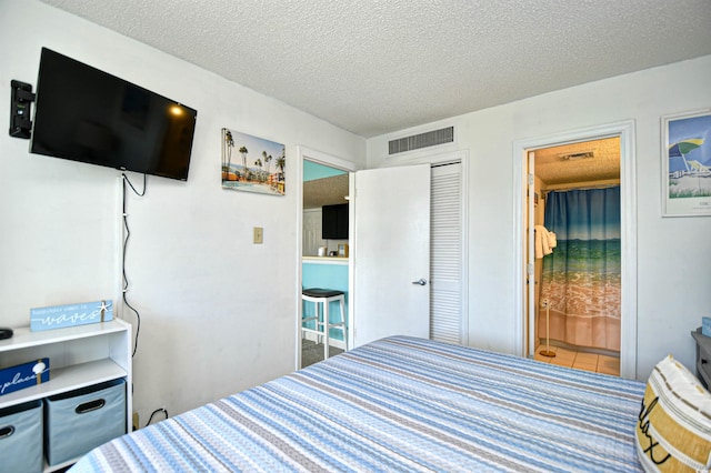 bedroom with ensuite bath, a closet, and a textured ceiling