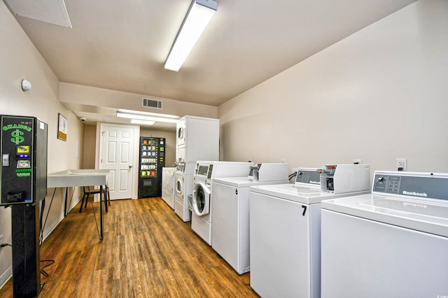 clothes washing area featuring stacked washer and dryer, dark wood-type flooring, and washing machine and clothes dryer