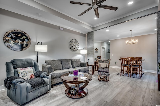 living room with ceiling fan with notable chandelier, ornamental molding, and light hardwood / wood-style floors