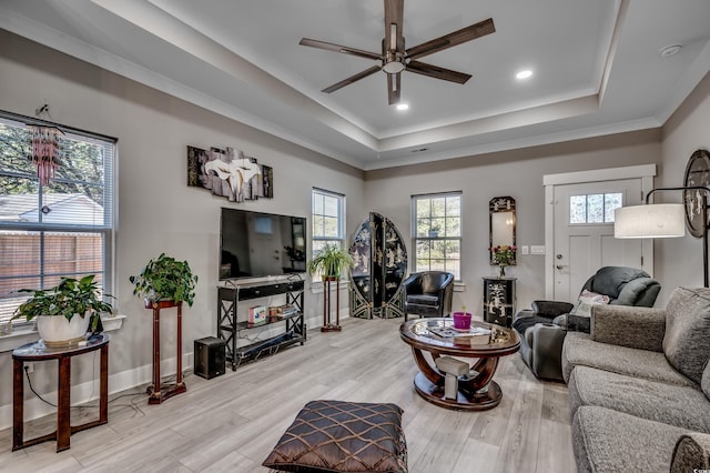 living room featuring ceiling fan, a healthy amount of sunlight, a raised ceiling, and light wood-type flooring