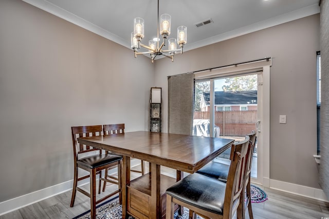 dining room featuring crown molding, an inviting chandelier, and hardwood / wood-style flooring