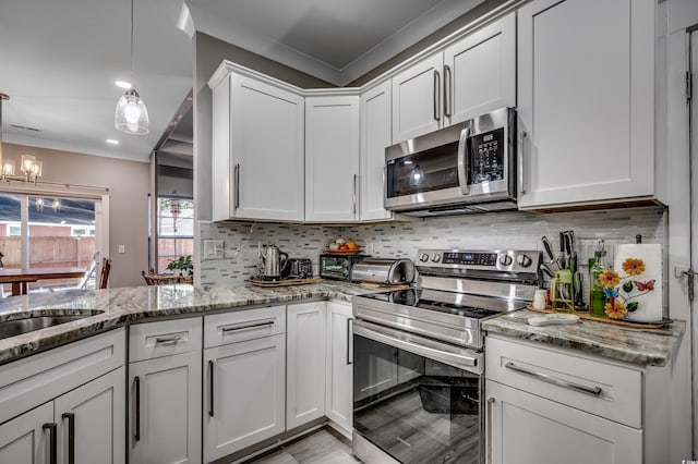 kitchen with white cabinetry, tasteful backsplash, light stone counters, hanging light fixtures, and stainless steel appliances