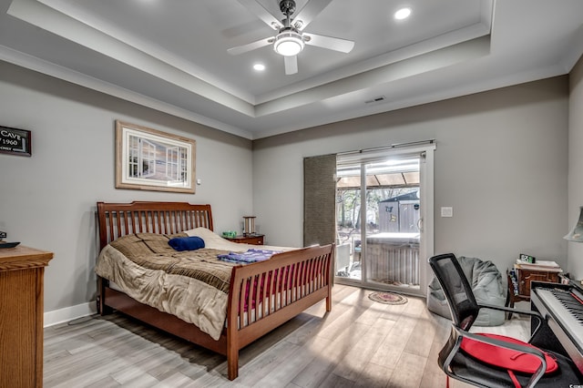 bedroom featuring ceiling fan, access to exterior, light wood-type flooring, and a tray ceiling