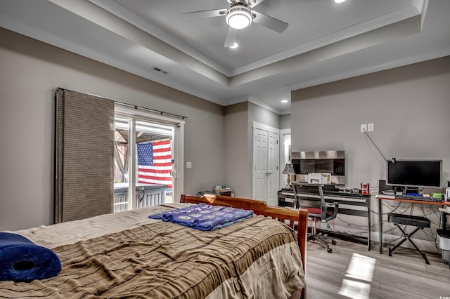 bedroom featuring ornamental molding, access to exterior, light hardwood / wood-style floors, a raised ceiling, and a closet