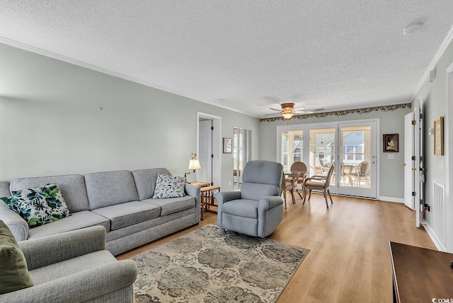 living room with ceiling fan, light hardwood / wood-style flooring, ornamental molding, and a textured ceiling