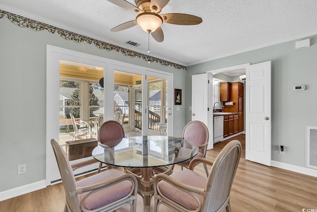 dining area with ceiling fan, sink, a textured ceiling, and light hardwood / wood-style flooring