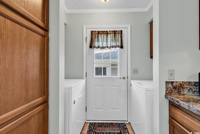 doorway with ornamental molding, washer and dryer, and a textured ceiling