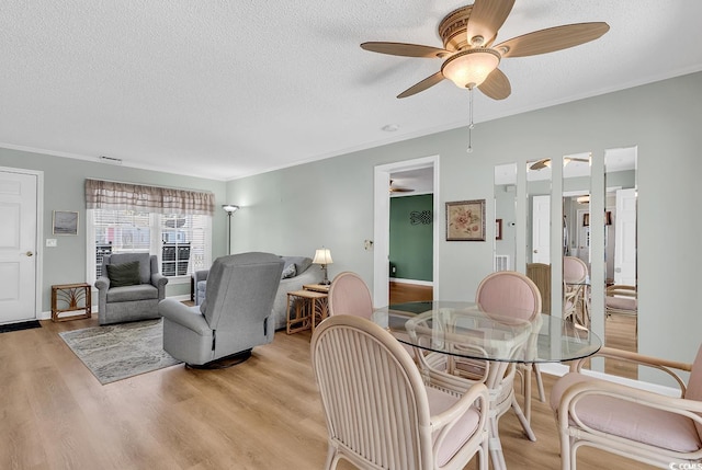 dining space with ceiling fan, ornamental molding, light hardwood / wood-style flooring, and a textured ceiling