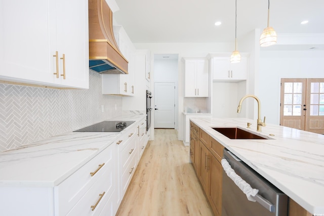 kitchen with sink, premium range hood, white cabinetry, hanging light fixtures, and black appliances