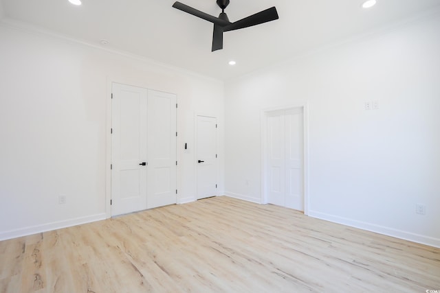 unfurnished bedroom with two closets, ornamental molding, ceiling fan, and light wood-type flooring