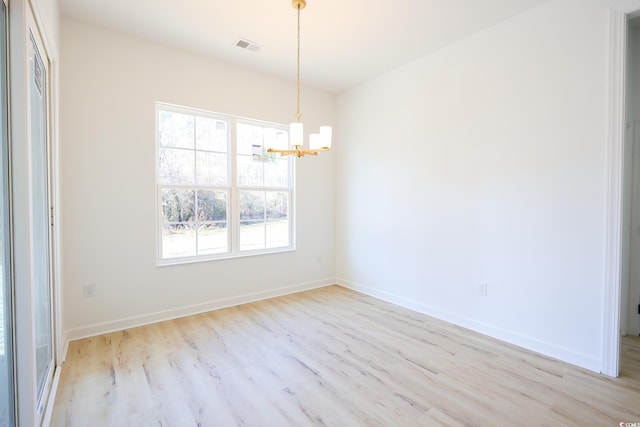 spare room with a chandelier and light hardwood / wood-style flooring