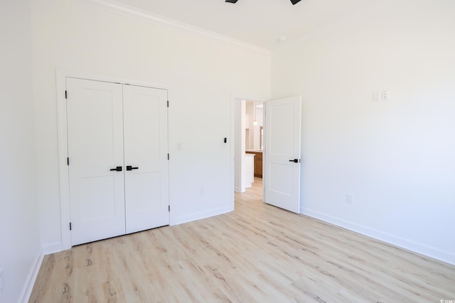 unfurnished bedroom featuring ornamental molding, ceiling fan, light wood-type flooring, and a closet