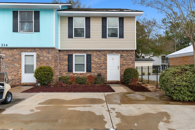 townhome / multi-family property with a patio area, fence, and brick siding