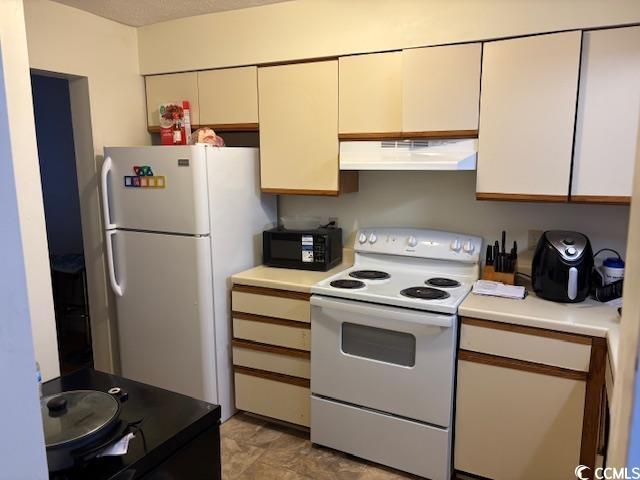 kitchen featuring under cabinet range hood, white appliances, and light countertops