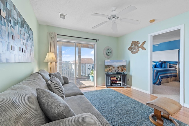 living room featuring a textured ceiling, ceiling fan, and light wood-type flooring