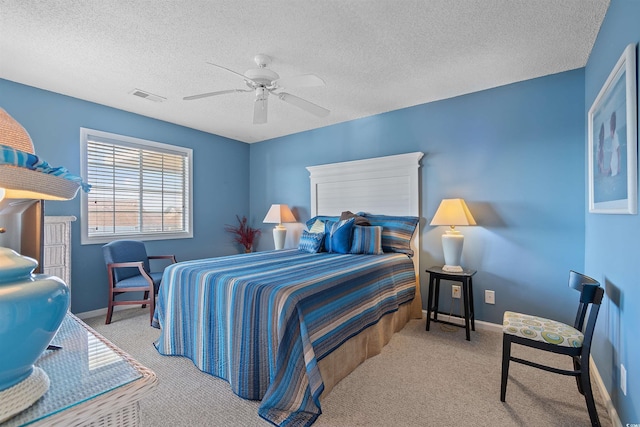 bedroom featuring ceiling fan, light carpet, and a textured ceiling