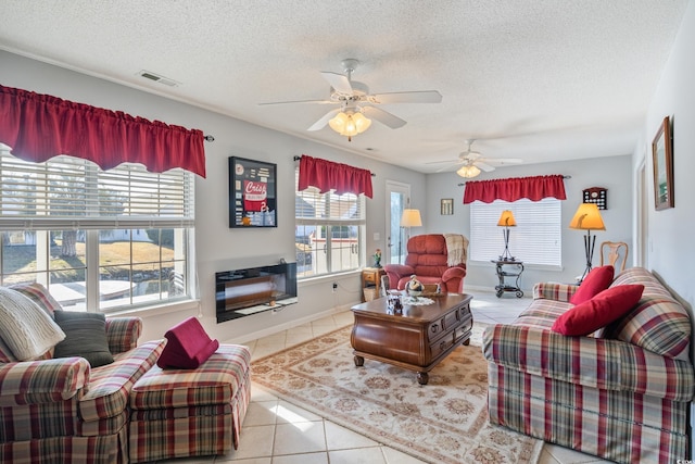 living room featuring light tile patterned flooring, ceiling fan, and a textured ceiling