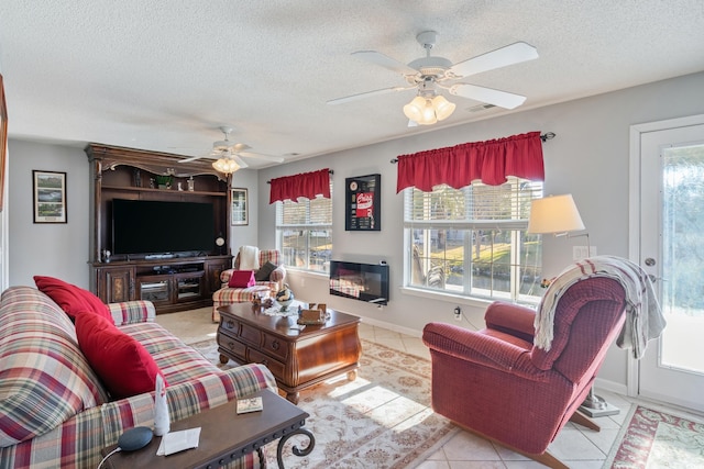 living room featuring ceiling fan, a textured ceiling, and light tile patterned floors