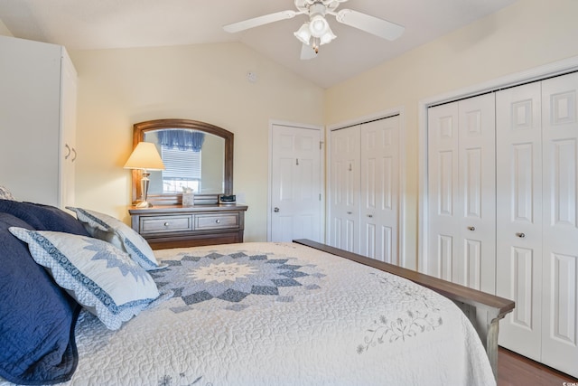 bedroom with ceiling fan, lofted ceiling, dark hardwood / wood-style flooring, and two closets