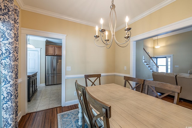 dining area featuring crown molding, a chandelier, and light hardwood / wood-style floors