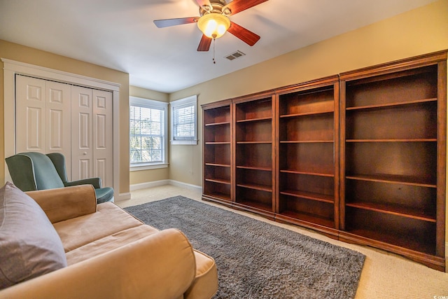 living area with light carpet and ceiling fan