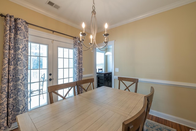 dining space featuring crown molding, wood-type flooring, and a chandelier